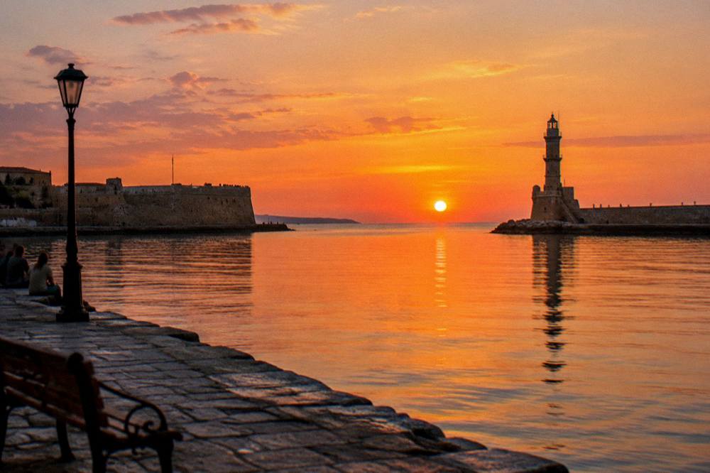 Evening view across the Venetian Harbour from the eastern quay towards the lighthouse and Firka Fortress