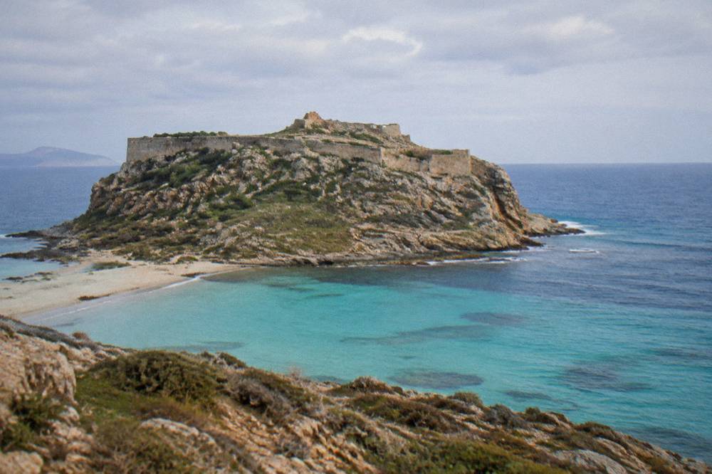 Stone fortress walls on a rocky island summit above open sea