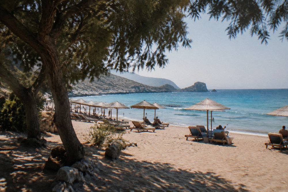 Sun loungers and umbrellas along a sandy shoreline in late afternoon light