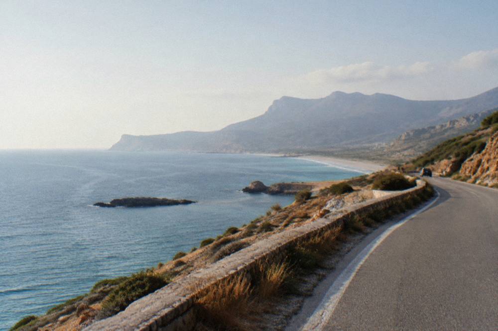 A coastal road curving along a hillside above open sea