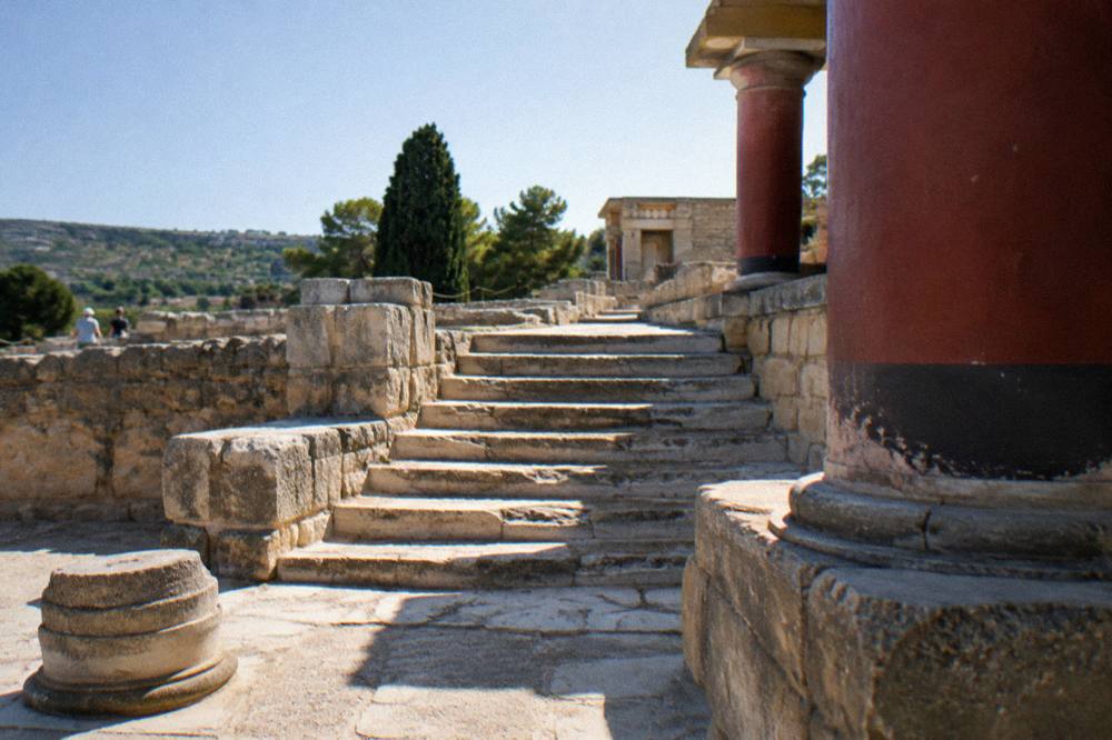 An ancient stone staircase and column bases at a palace site under strong midday sun