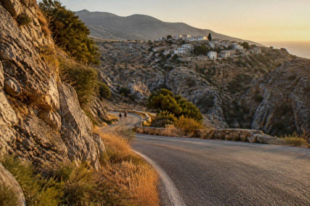 A mountain road winding through dry hills toward a village on a ridge