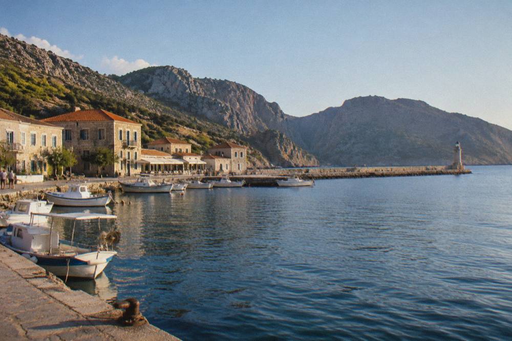 The seafront of a harbour town with historic stone buildings and a long mole