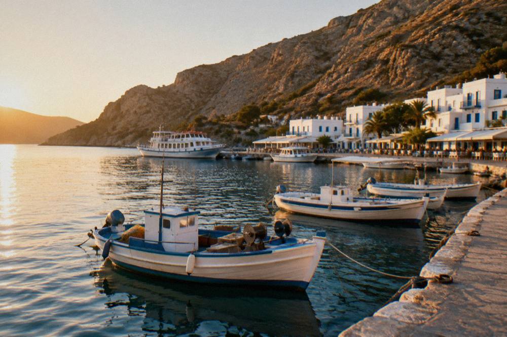 Fishing boats and a small ferry tied along a stone quay in a south coast harbour village