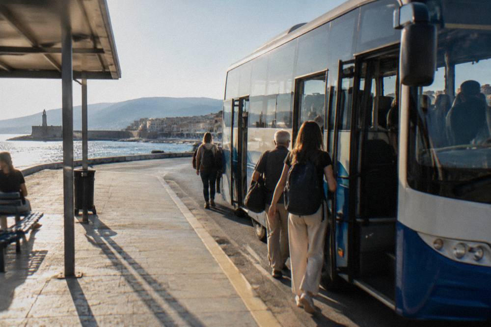 An intercity bus parked at a small station platform with passengers boarding