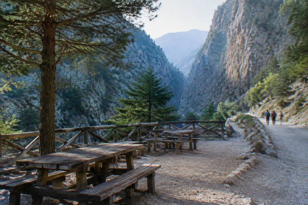 A wooden park beside a mountain trail with high cliffs behind it