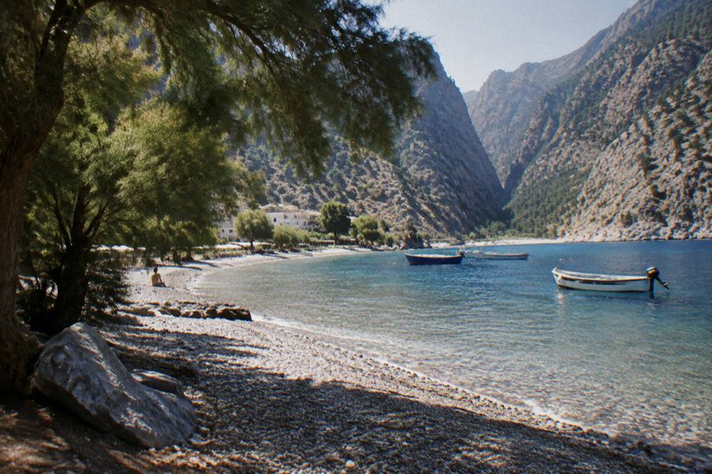 A small coastal village at the mouth of a gorge with a pebble beach and boats