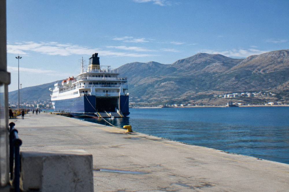 A large ferry berthed at Souda port with hills behind the bay in morning light