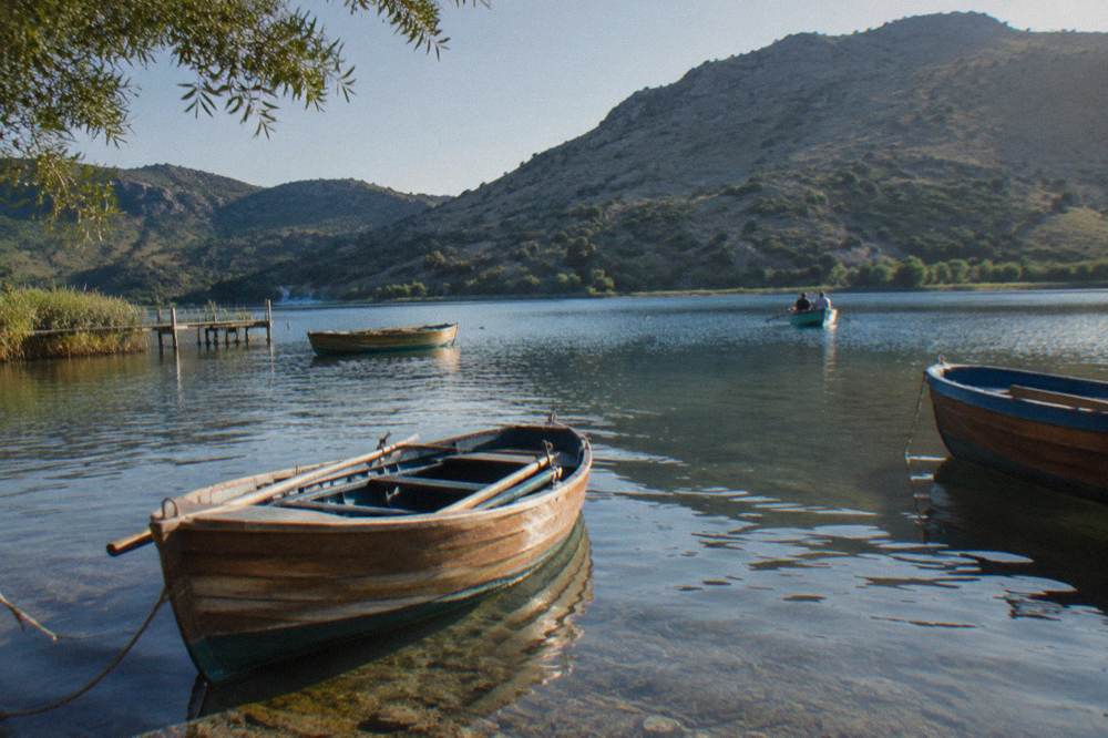 Wooden rowing boats on the still water of Lake Kournas ringed by hills