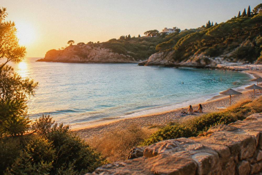 A sheltered turquoise bay with a few umbrellas and wooded slopes on three sides