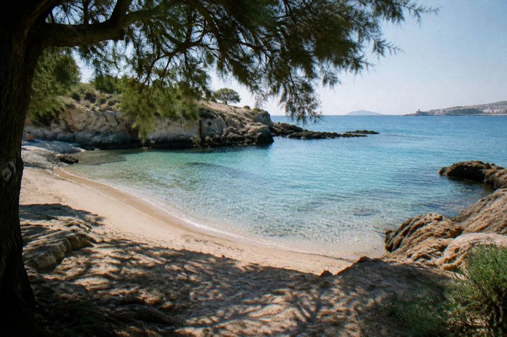 An empty sandy cove with clear water and rocky headlands in early morning light