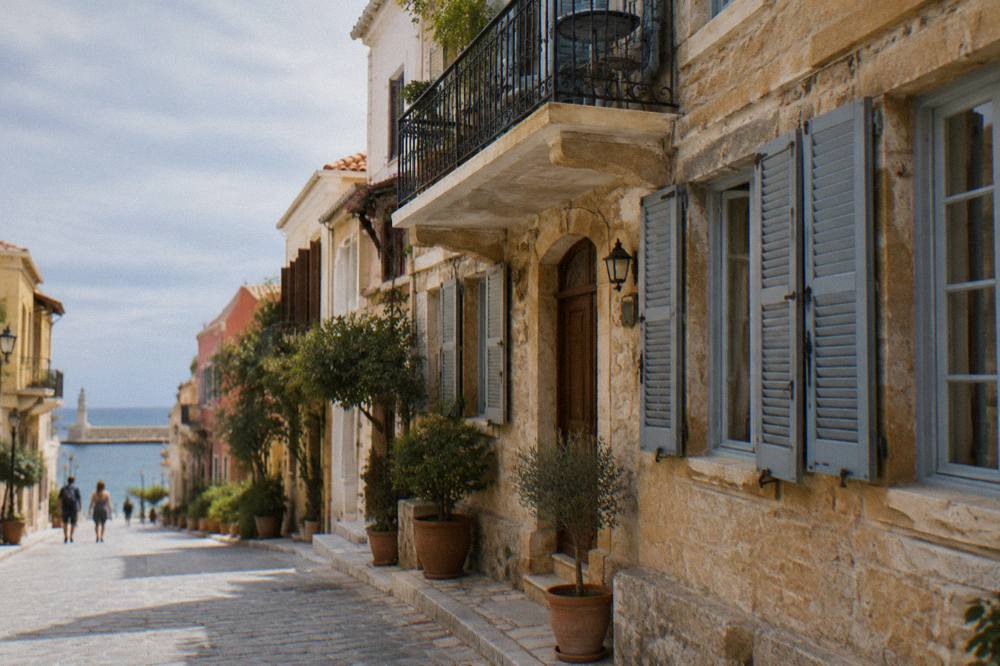 Wooden shutters and a balconied hotel facade on a sunlit Chania street