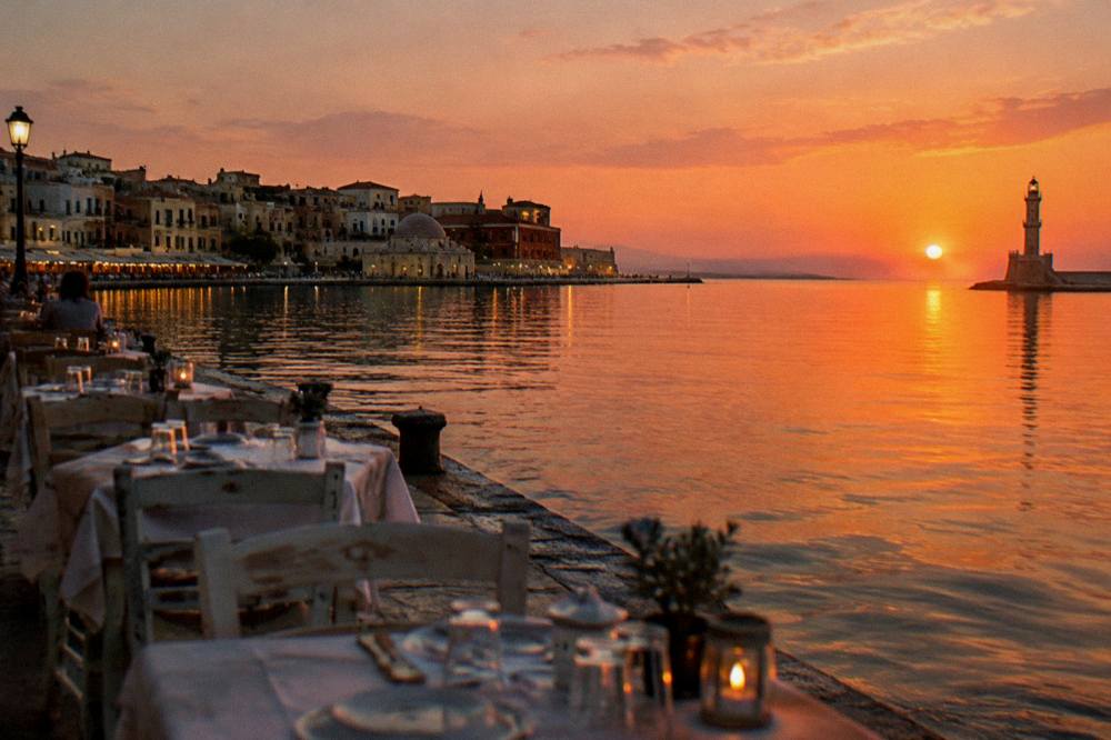 Tables set for dinner beside the water at dusk in Chania harbour