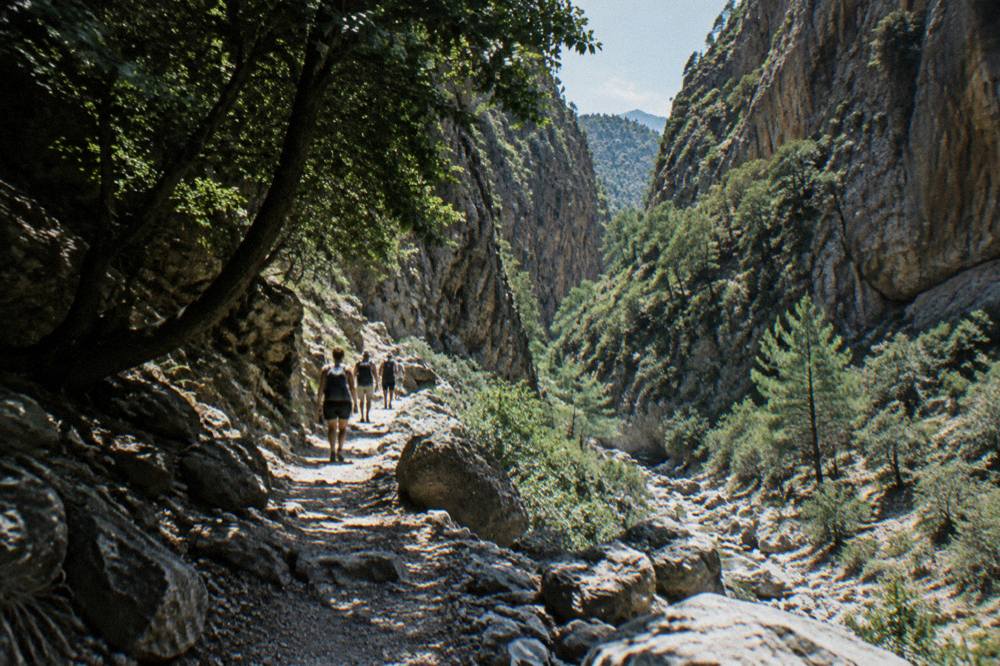 Hikers on a rocky path inside a steep gorge in western Crete