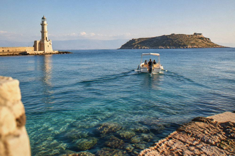 A small boat crossing clear shallow water toward an island