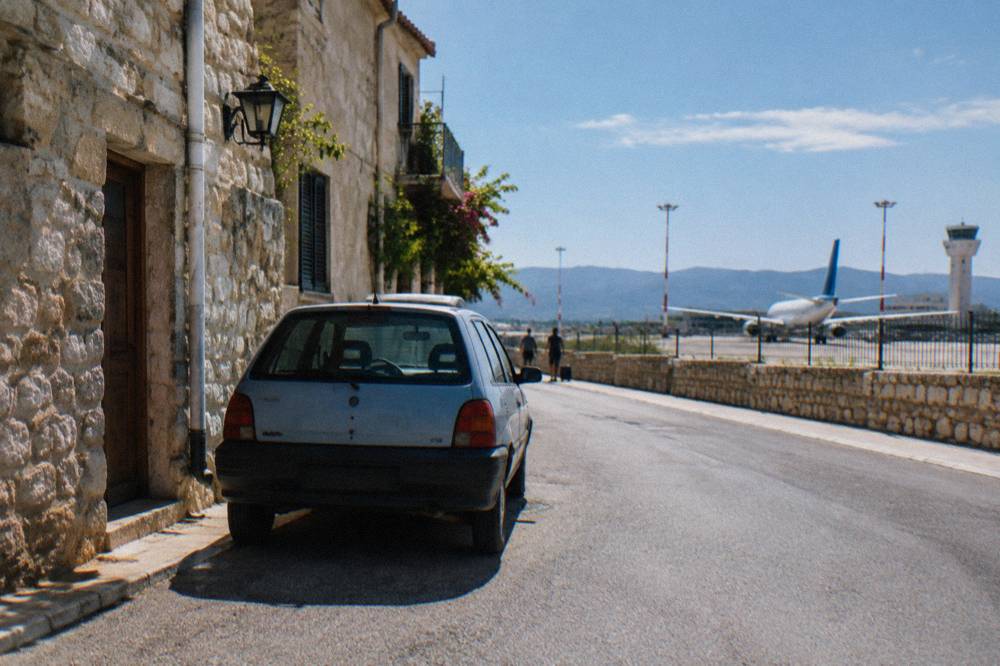 A small hatchback parked on a narrow street beside old stone buildings