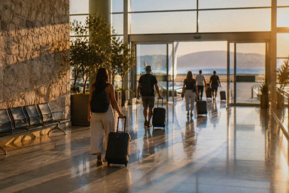 Travellers with suitcases walking through a bright airport arrivals corridor toward the exit doors
