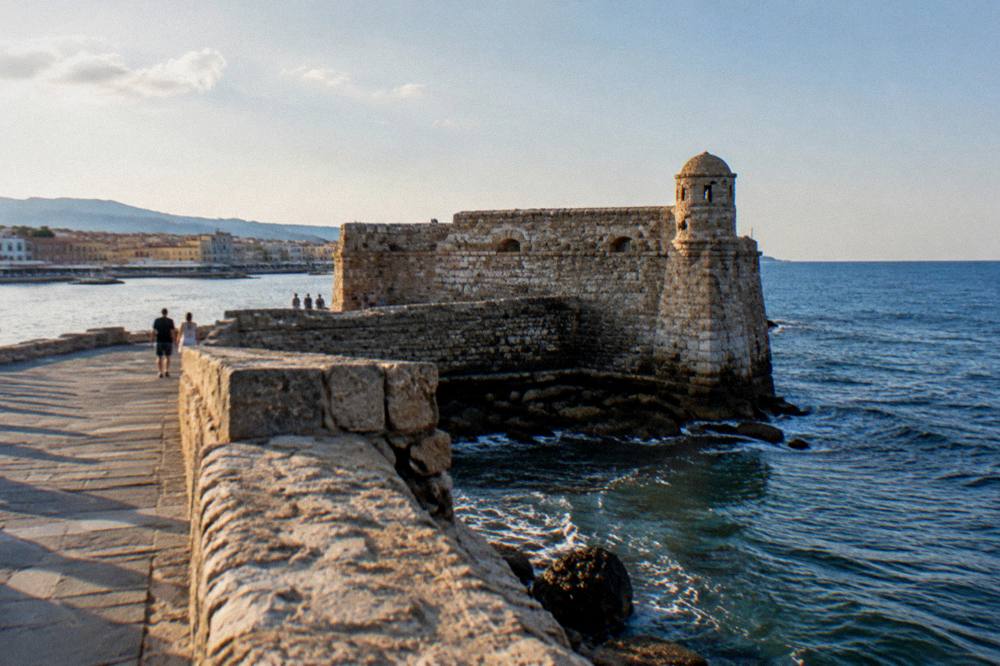 Stone walls of Firka Fortress at the harbour entrance with the sea behind
