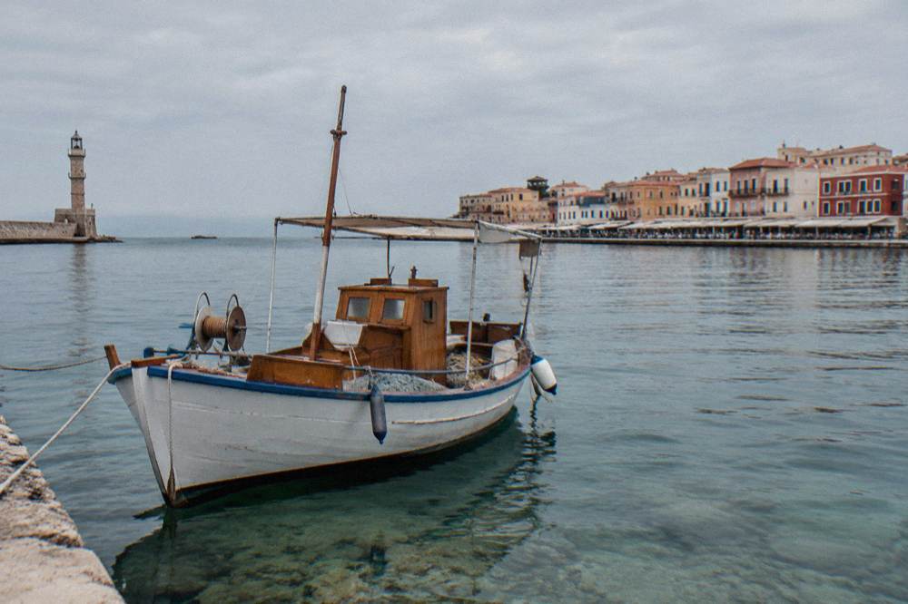 A traditional wooden boat at anchor in clear shallow water near Chania