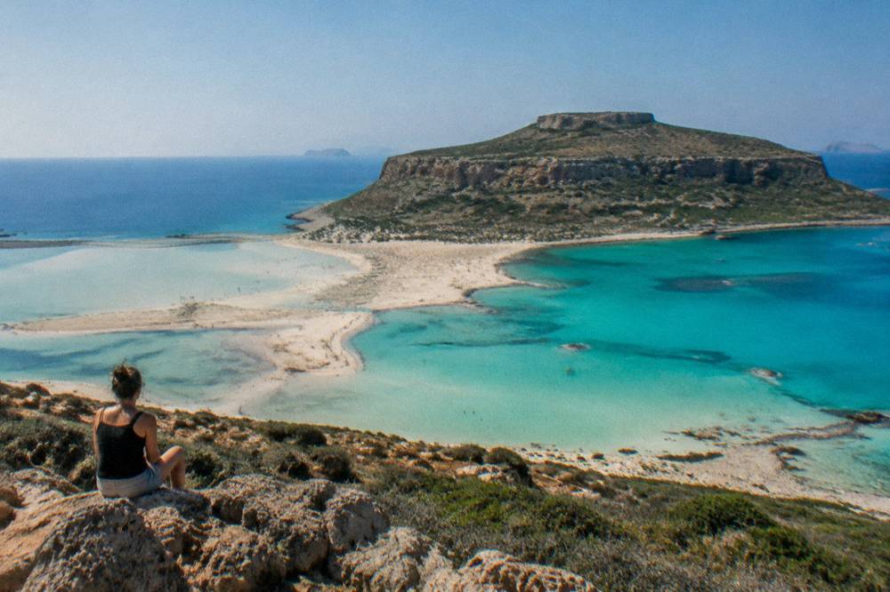 Turquoise shallow water of Balos lagoon seen from the hill above, with a strip of sand between two bays