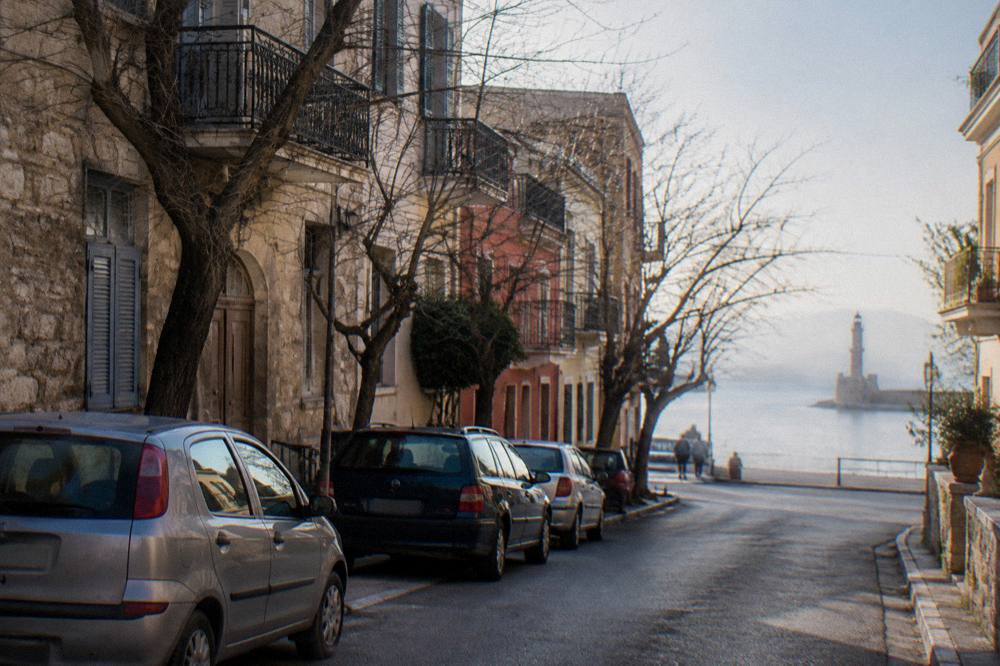 A quiet street in Chania with parked cars and leafless trees in soft winter light