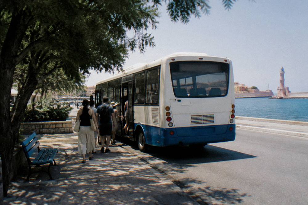 A local bus parked at a small station in Crete with passengers boarding
