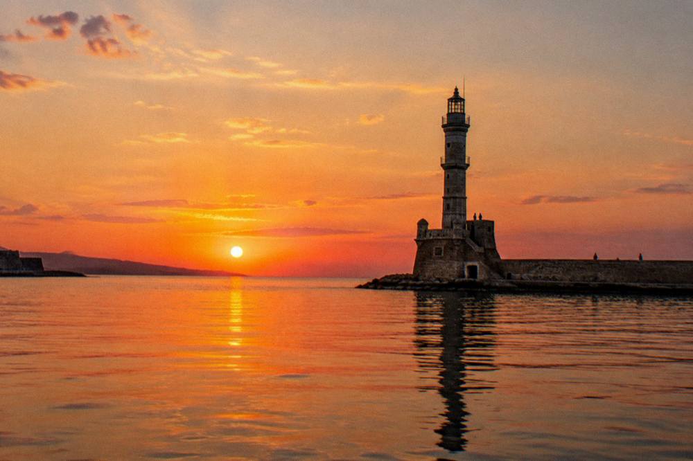 The Chania lighthouse and harbour mole seen from the water at sunset