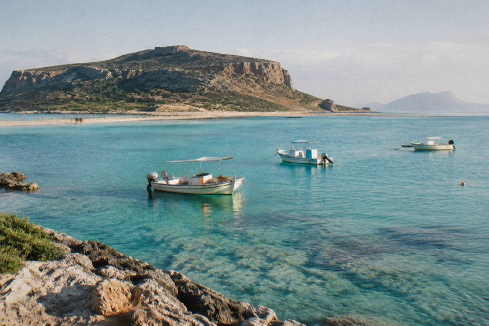 Small boats moored in clear turquoise water at Balos lagoon