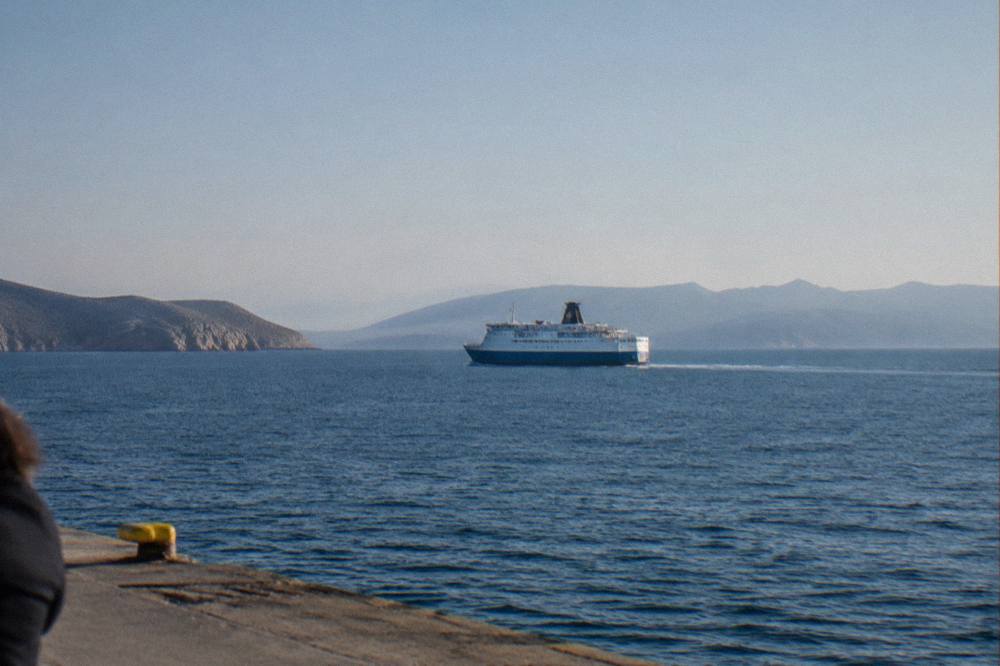 A ferry at sea between Greek islands under a clear sky