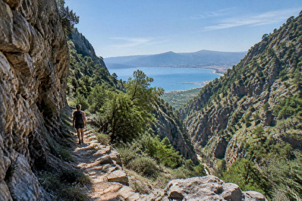 A hiker on a rocky path inside a deep gorge in Crete