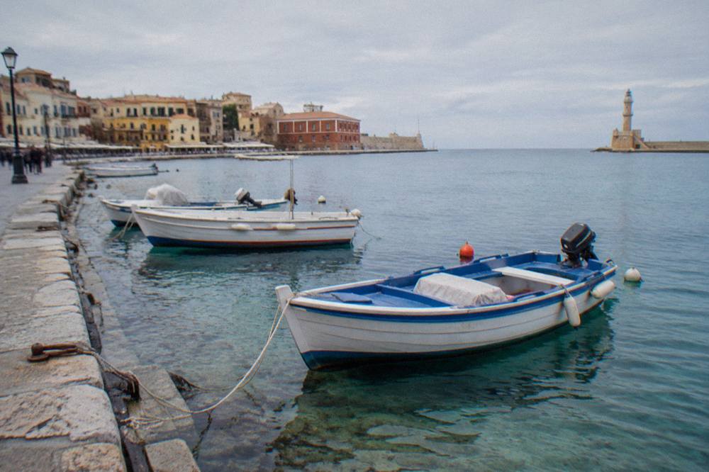 Small boats moored in clear shallow water beside a stone quay