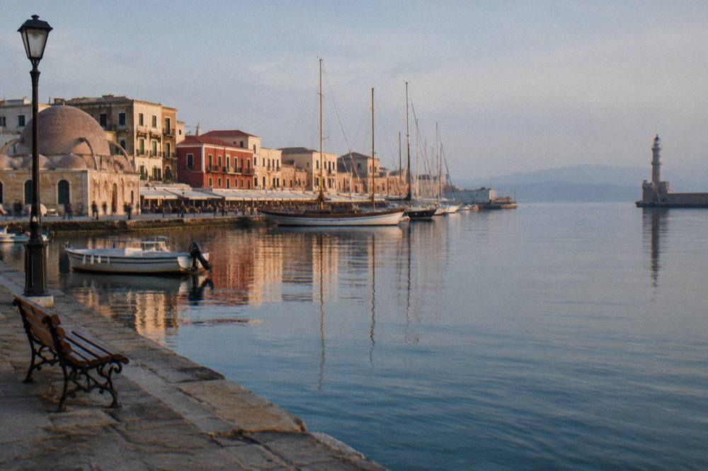 Harbour water reflecting the stone facades and wooden masts along the Chania waterfront