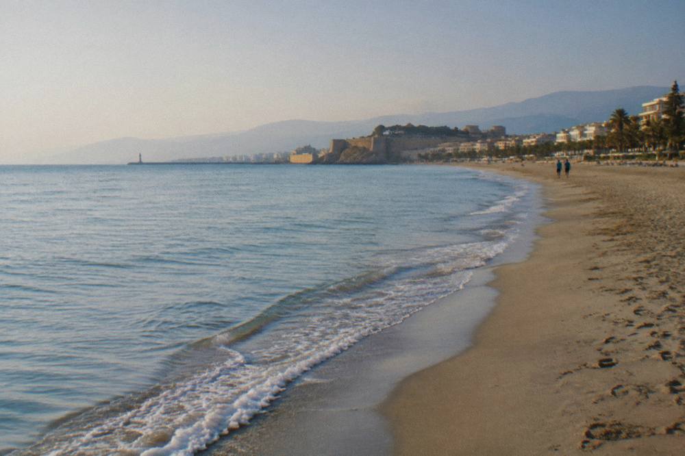 A long sandy beach curving away from a town edge along a calm northern sea