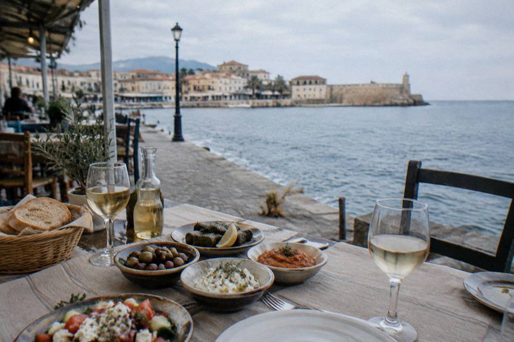 A taverna table with small Cretan dishes, bread, olive oil and glasses of wine