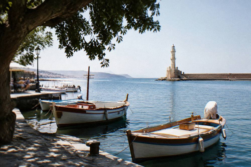 Wooden boats moored in the old harbour with the lighthouse in the distance