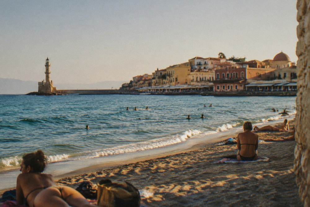Sunbathers on a sandy beach near Chania under strong midday sun