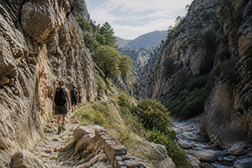 Hikers on a rocky gorge path beneath high stone walls in Crete