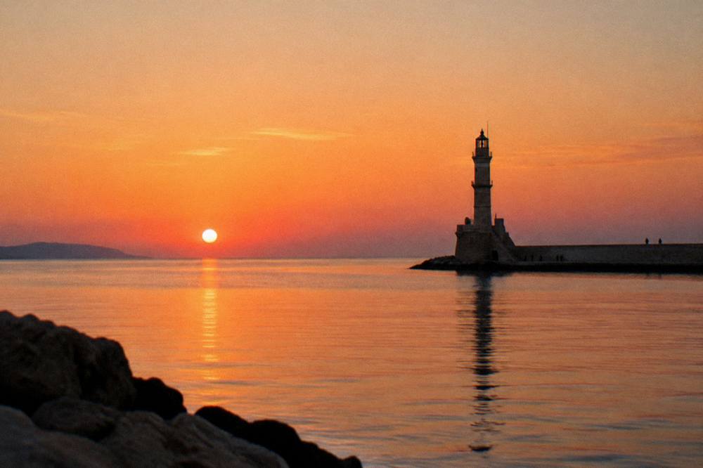 The Chania lighthouse at sunset with a calm sea and clear evening sky