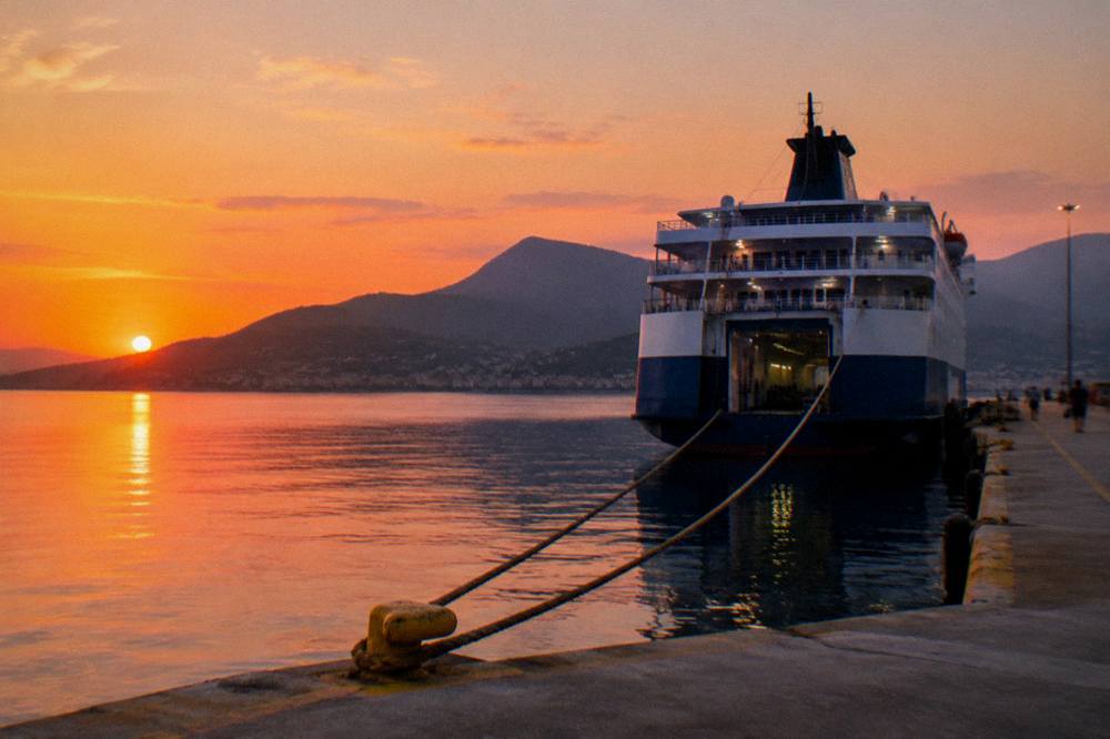 A ferry tied at a port quay in evening light with hills behind