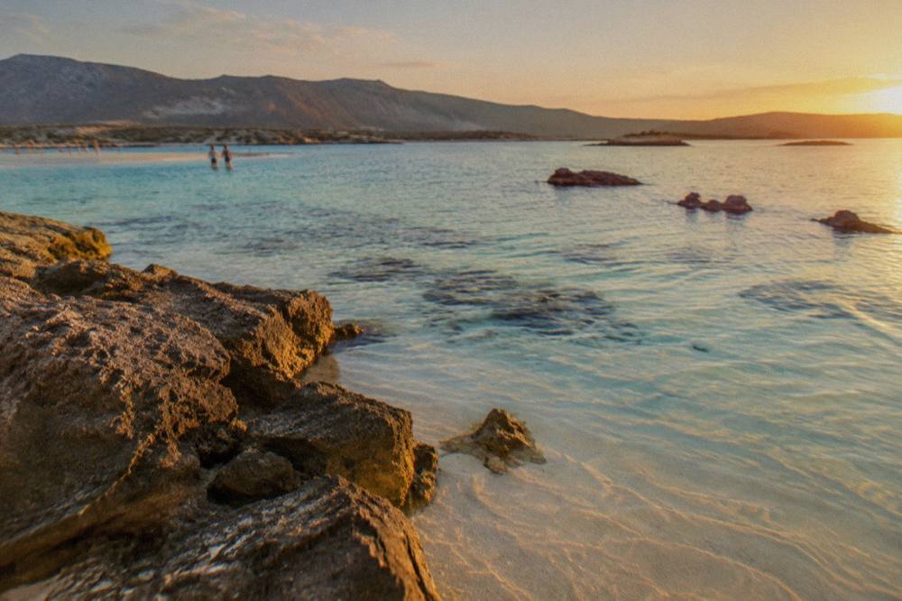 Shallow turquoise water over pale sand with distant hills across the lagoon