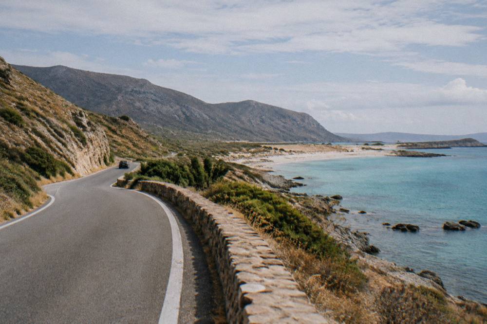 A coastal road winding between dry hills and the sea