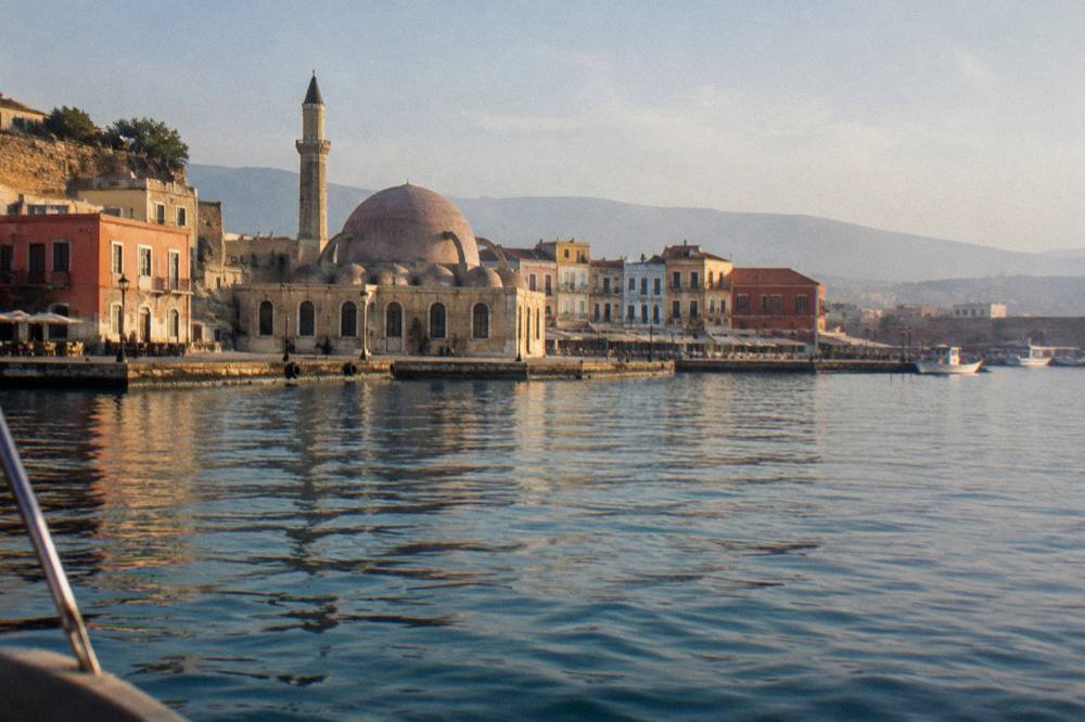 The seafront of Chania seen from the water with the mosque and harbour buildings along the quay