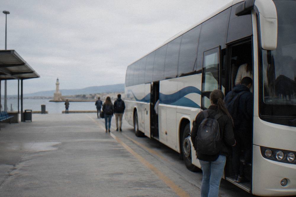An intercity bus parked at a Greek bus station with passengers boarding
