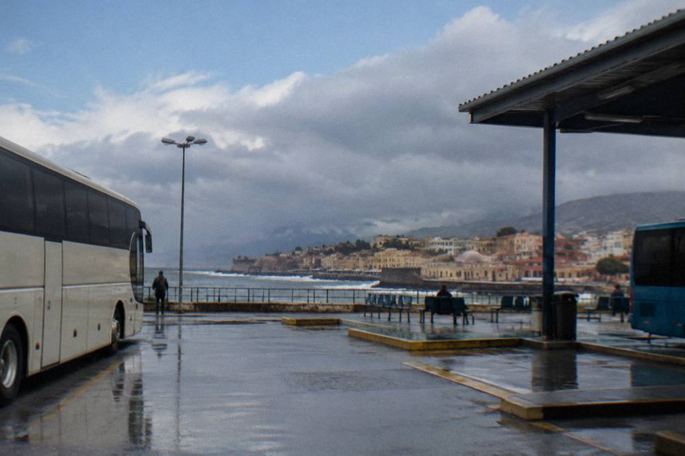 Rain clouds over a Cretan coastal town with wet rooftops and a grey sea