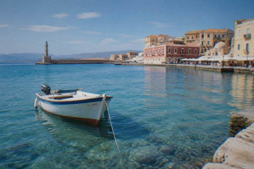 A small boat anchored in the shallow turquoise water of a Cretan lagoon