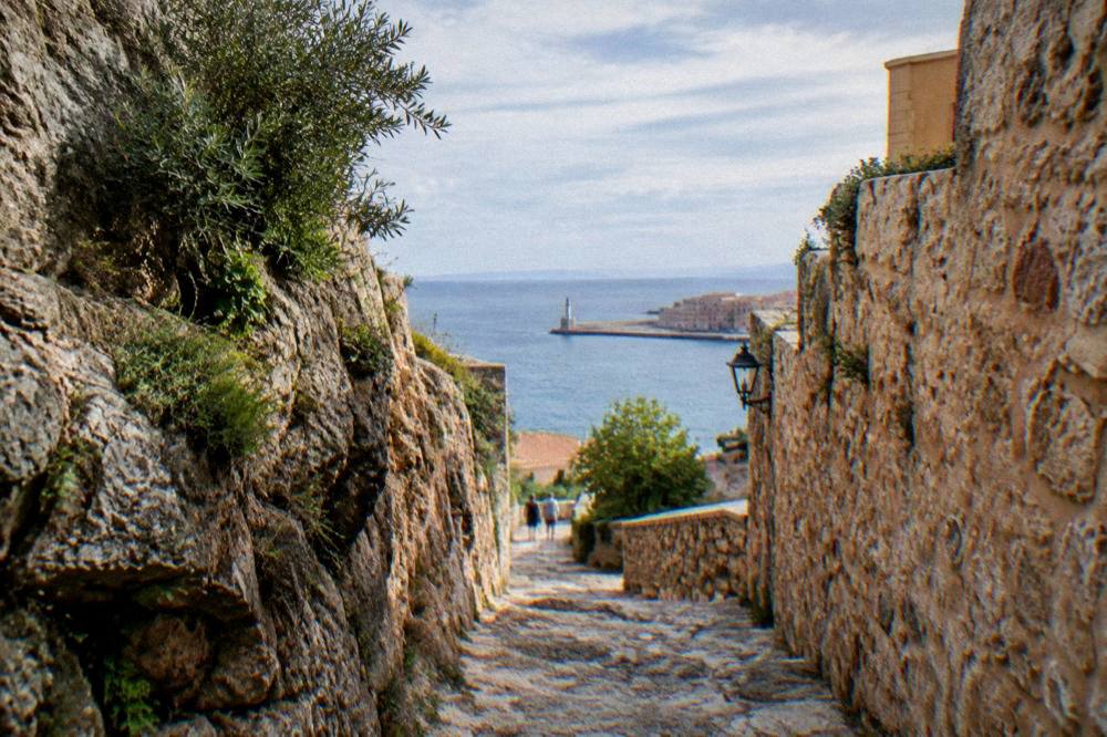A rocky gorge path descending between high stone walls toward distant sea