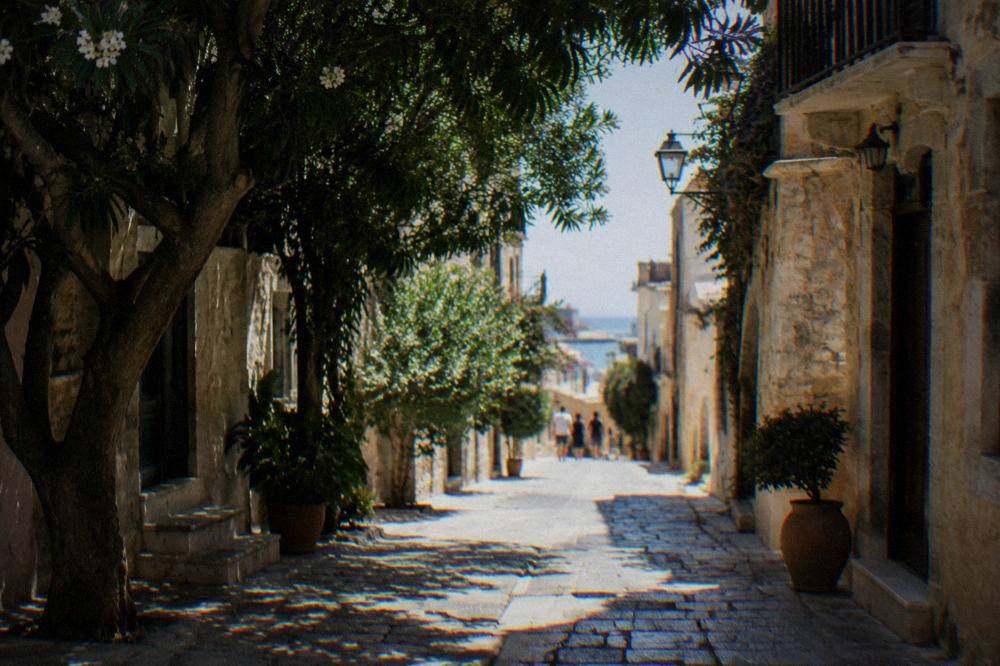 A narrow stone-paved street in Chania Old Town with restored buildings and shaded walkways