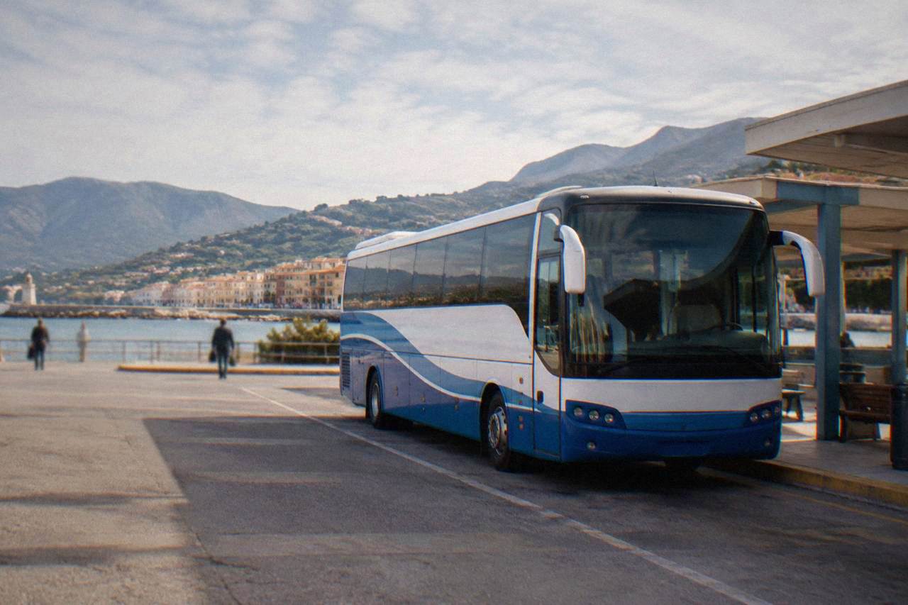 Blue and white intercity bus parked at a station in Chania with hills behind it