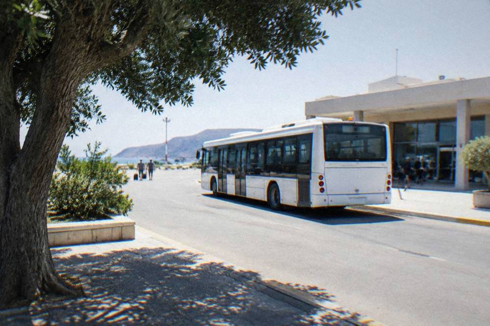 Airport bus parked outside a small terminal building on a clear afternoon