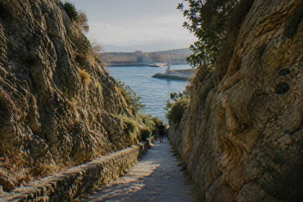 Narrow walking path descending between high rock walls in a Cretan gorge